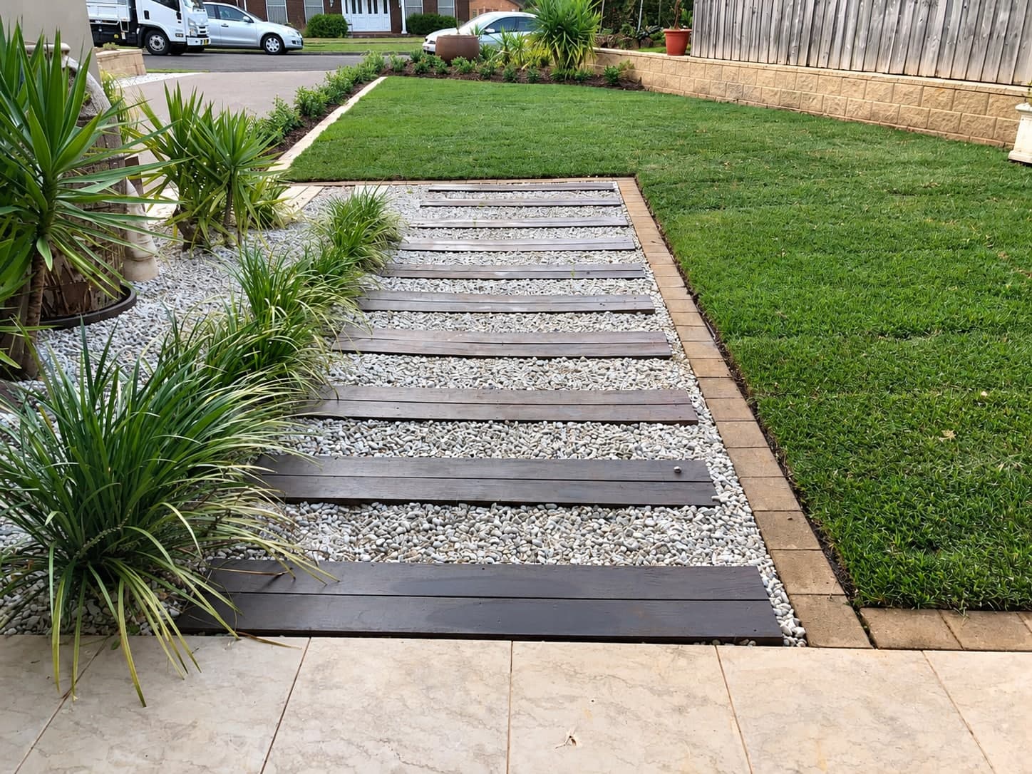 A timber and gravel path beside new lawn and planting