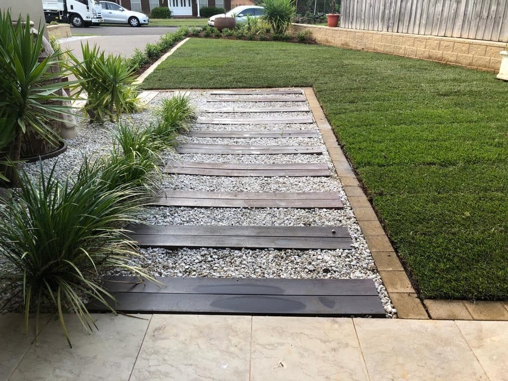 A timber and gravel path beside new lawn and planting