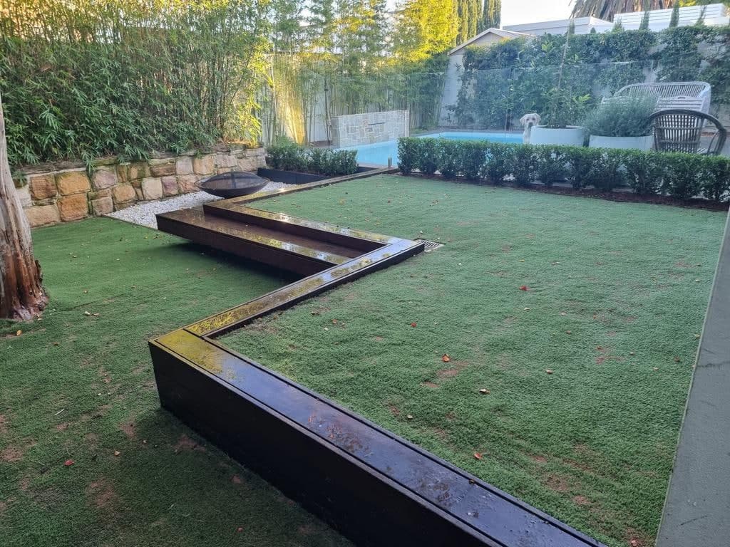 Angular timber edging and a low platform beside planted borders in Pymble