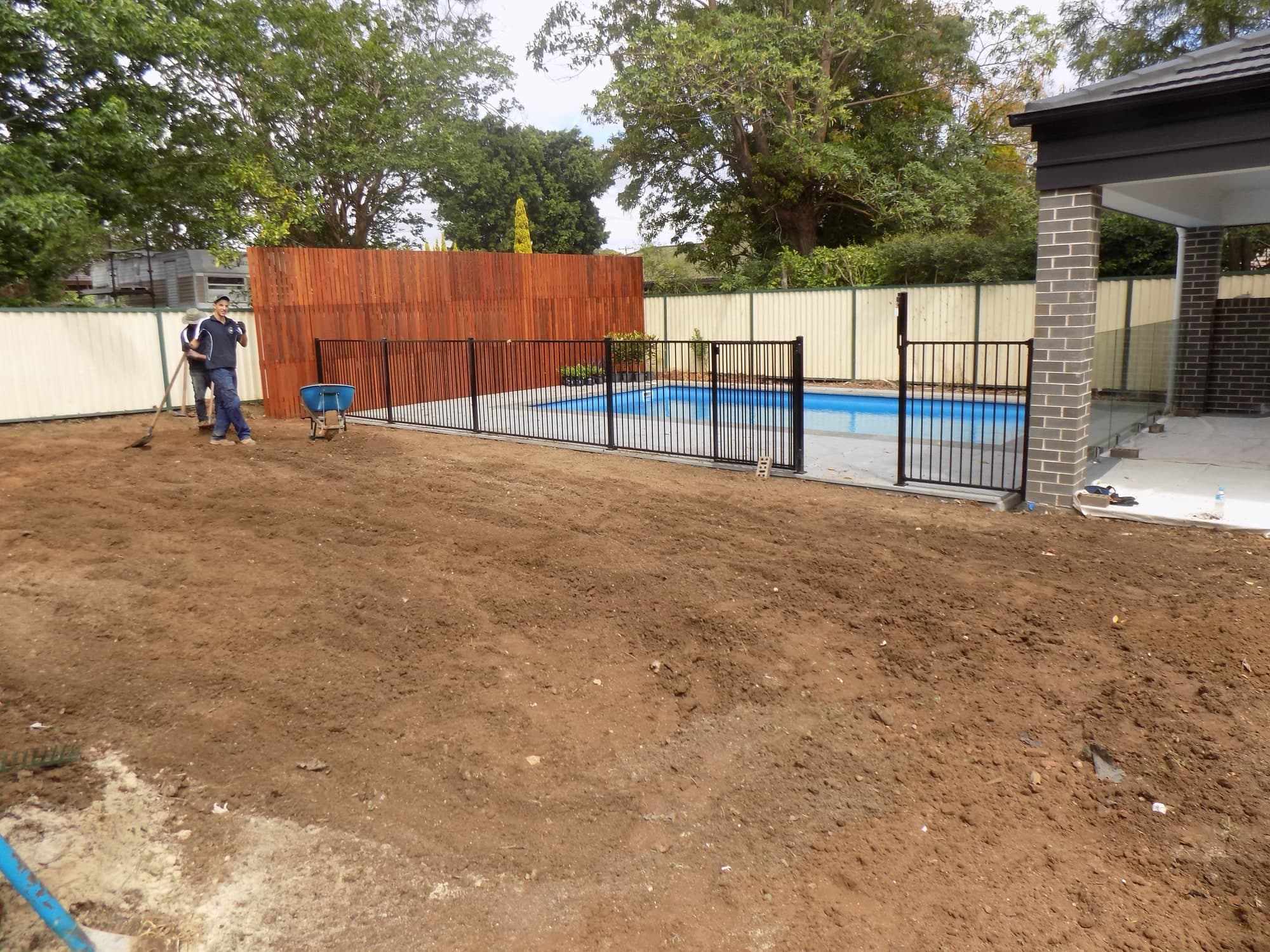 Bare, rough ground beside a new pool fence before the job